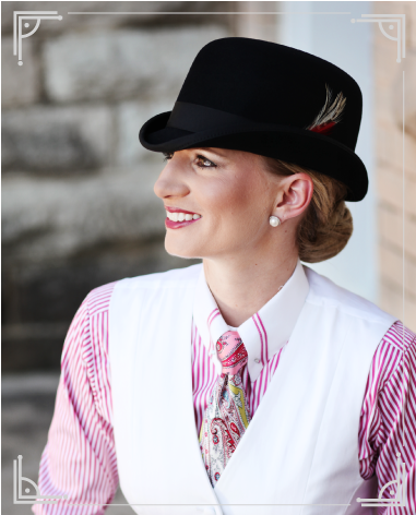 Girl wearing a red and white stripped shirt, white vest, black hat with a feather in it